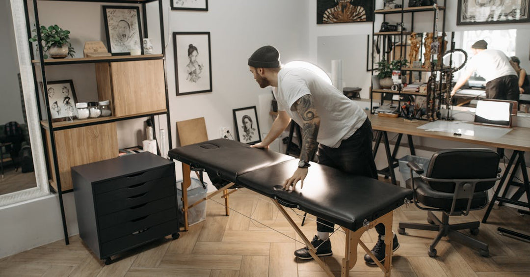 Tattoo artist adjusting ergonomic tattoo chair in a modern, aesthetic studio setup